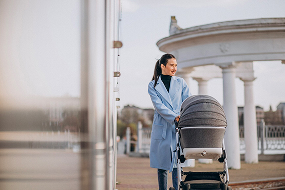 A mother walking with baby in a travel stroller