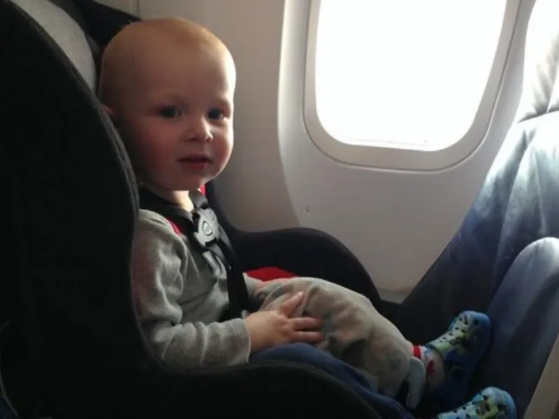 baby sitting on the car seat on the plane